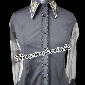 Pu&ograve; includere: Una camicia nera a maniche lunghe con un colletto tempestato di strass e una singola fila di strass sul davanti. La camicia ha maniche in rete trasparente. Il testo "Theequinestoreindia" &egrave; visibile sulla camicia.