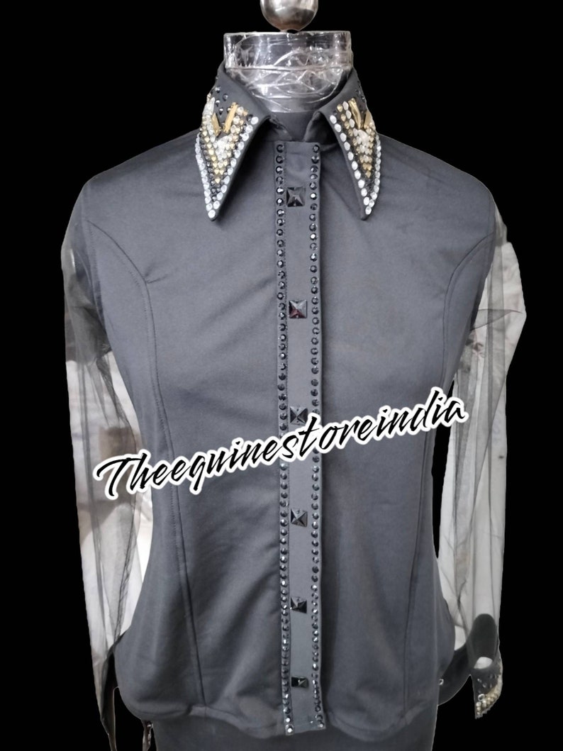 Pu&ograve; includere: Una camicia nera a maniche lunghe con un colletto tempestato di strass e una singola fila di strass sul davanti. La camicia ha maniche in rete trasparente. Il testo "Theequinestoreindia" &egrave; visibile sulla camicia.
