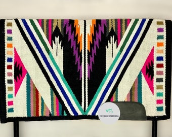 May include: A colourful saddle pad with a geometric pattern in shades of pink, green, blue, orange, and white. The pad has a black background and a grey suede patch with the text "TheeQuineStoreIndia".