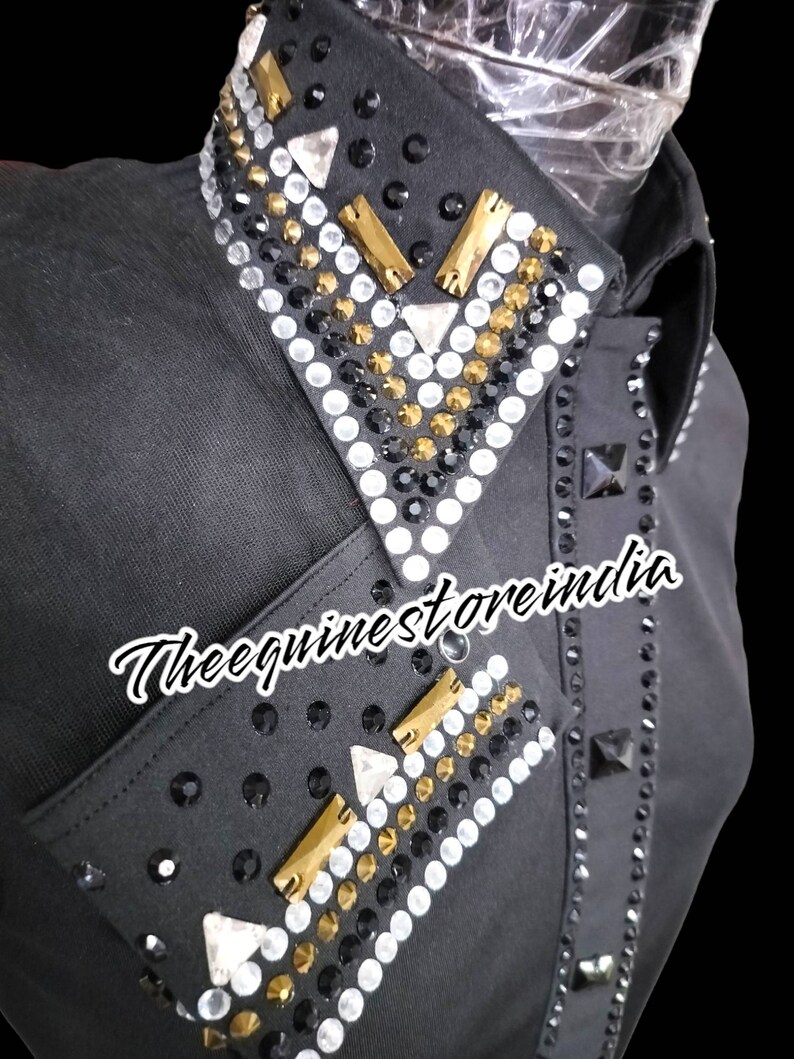 Pu&ograve; includere: Camicia nera a maniche lunghe con un design di strass dorati, bianchi e neri sul colletto e sui polsini. Il testo "Thee equinestorerindia" &egrave; stampato sulla camicia.