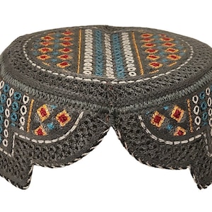 May include: A gray embroidered cap with a geometric pattern in shades of blue, red, and gold. The cap has a rounded top and a flat brim.