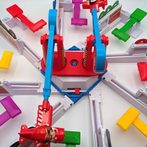 Könnte beinhalten: Ein farbenfrohes Spielzeug-Flugzeug-Karussell-Set mit roten, blauen und weißen Komponenten. Das Set enthält Miniatur-Rotflugzeuge mit Pilotenfiguren, die mit einer zentralen Struktur verbunden sind. Verschiedene farbige Hebel und Bahnen umgeben das Karussell und schaffen ein verspieltes und ansprechendes Design.