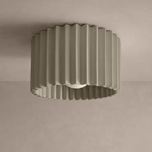May include: A circular ceiling light fixture featuring a matte, light taupe exterior with a vertical, fluted, or pleated texture. The cylindrical shade has an open bottom design, revealing a single, centred, white spherical light bulb inside.