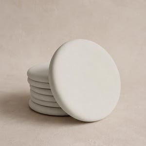 以下が含まれることがあります： 滑らかでマットな質感のオフホワイトの円形コースター6枚セット。各コースターは均一な丸みを帯びた縁と平らな表面を備えています。コースターは少しずらして垂直に積み重ねられており、その一貫した形状と色合いがはっきりと確認できます。