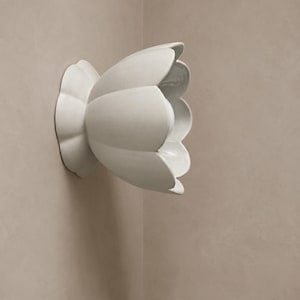 May include: A wall-mounted light fixture shaped like a blooming flower with smooth, matte, off-white petals. The structure features a central circular base that attaches to the wall, supporting a wide, open, petal-like shade with a light bulb inside.
