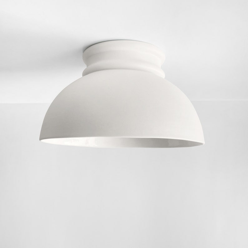 Op de afbeelding: Witte plafondlamp met een afgeronde koepelvorm.