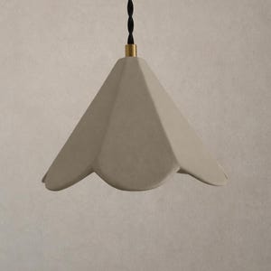 May include: A beige, petal-shaped pendant light. The light has a textured surface and a black cord with a gold-coloured accent at the top. The light is suspended from the ceiling.