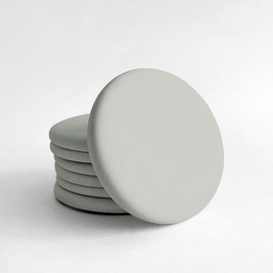 Peut inclure: Un ensemble de six sous-verres ronds de couleur gris clair. Les sous-verres sont faits d'un matériau lisse et doux.