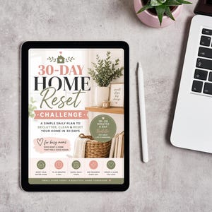 May include: A digital tablet displaying a 30-Day Home Reset Challenge guide. The screen features text, a house icon, a woven basket, and a plant. The layout includes a daily plan, a 15-20 minutes a day badge, and five circular icons at the bottom.