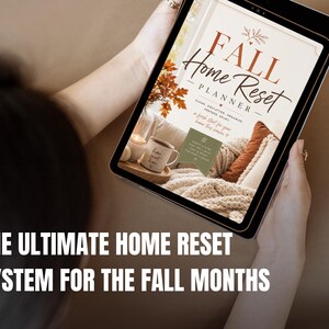 May include: A digital tablet displaying a planner cover titled Fall Home Reset Planner. The design features warm autumn colors, a cozy interior scene with a mug, and text that reads Clean, Declutter, Organize, Prepare, Enjoy, a fresh start for your home this season.