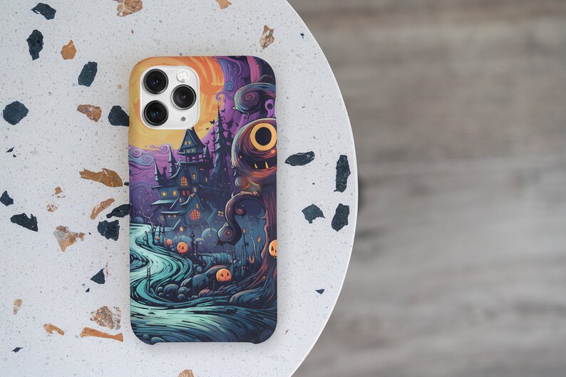 May include: A phone case with a Halloween theme. The case features a spooky house, a creepy tree, and a moon with a face. The colours are purple, blue, orange, and black.