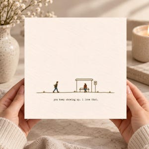 May include: A square greeting card with a cream-coloured background featuring a minimalist line drawing of a bus stop. A person walks towards a seated figure at the stop. The text reads: you keep showing up. i love that.