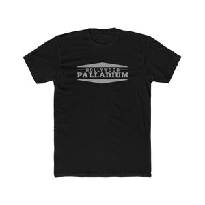 May include: Black t-shirt with a gray geometric design and the text "HOLLYWOOD PALLADIUM". The design is a stylized, symmetrical shape with the text centered within it. The shirt is made of a soft material.