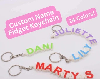 May include: Customizable name keychain made of colorful plastic letters. The keychain is attached to a silver key ring. The image shows three keychains with the names "Marty", "Dani", and "Juliette". The text "24 Colors!" is visible in the image.