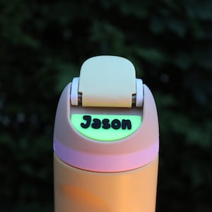 May include: A beige and light pink water bottle with a light green lid and a black name tag that says "Jason".