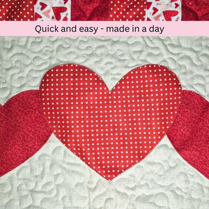 May include: A quilted textile featuring three red hearts on a white background. The central heart has a white polka dot pattern. The text "Quick and easy - made in a day" is displayed above the hearts.