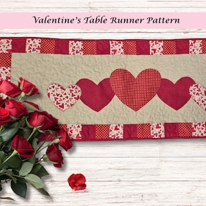 May include: A Valentine's Day table runner with a beige center and red borders. The runner features five heart appliqués in varying red patterns. A bouquet of red roses is in the foreground. The text "Valentine's Table Runner Pattern" is at the top.