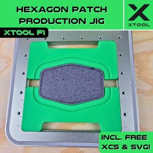May include: A metal and green hexagon patch production jig with the text "HEXAGON PATCH PRODUCTION JIG" and "XTOOL" in green and white. A grey felt hexagon patch is centered within the jig. The text "INCL. FREE XCS & SVG!" is also visible.