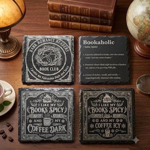 May include: Four square black slate coasters with white engraved text and illustrations. One features a book club design, one defines bookaholic, and two display the text I like my books spicy and my coffee dark or icy with decorative borders.