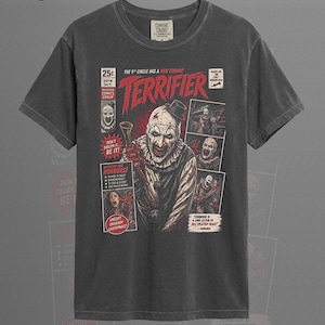 May include: A graphite-coloured t-shirt featuring a graphic print designed like a vintage comic book cover for the film Terrifier. The print includes the title Terrifier in red, a central clown character, and various smaller panels with horror imagery and text.
