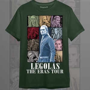 May include: Forest green t-shirt featuring a collage of images of Legolas, with the text "LEGOLAS THE ERAS TOUR" in white. The shirt has a crew neck and short sleeves. The brand name "Magnum" is printed on the upper chest.