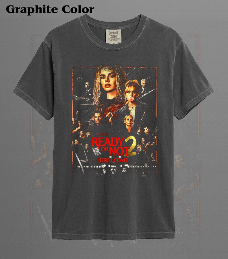 May include: A graphite-colored short-sleeve t-shirt featuring a graphic print of the movie poster for Ready or Not 2. The design includes multiple character portraits in a dark, cinematic style with the red and yellow text Ready or Not 2 Here I Come.