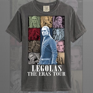 May include: Pepper color t-shirt featuring a collage of images of Legolas from The Lord of the Rings. The design includes the text "LEGOLAS THE ERAS TOUR" in white block letters. The shirt has a crew neck and short sleeves.