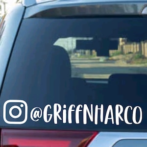 May include: White vinyl decal with an Instagram logo and the text "@GRIFFINHARCO" on a blue car window.