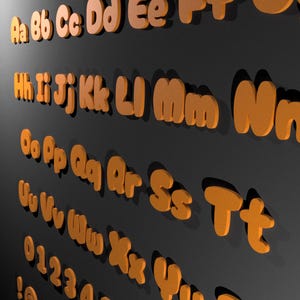 May include: Orange, three-dimensional alphabet letters and numbers against a dark grey background. The letters are in a playful, rounded font, with both uppercase and lowercase letters visible. The numbers 0-4 are also present.
