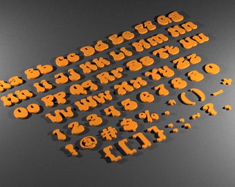 May include: Orange felt letters and numbers in a retro style font. The letters are arranged in alphabetical order and the numbers are in numerical order. There are also punctuation marks and symbols.