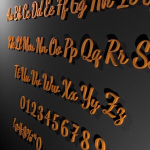 May include: Orange wooden alphabet letters and numbers in a cursive font are arranged on a dark gray background. The letters include uppercase and lowercase, along with numbers and symbols.