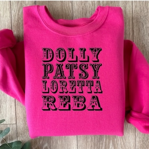 May include: A hot pink sweatshirt with black text that reads "DOLLY PATSY LORETTA REBA".