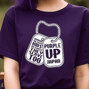 Puede incluir: Camiseta Purple Up for Japan con un gráfico blanco de dos chapas de perro. El texto en las chapas de perro dice "Honrar a los niños militares porque ellos también sirven" y "Purple Up Japan".