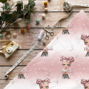 Könnte beinhalten: Ein rosa-weißes Stoffmuster mit einer sich wiederholenden Illustration eines Mädchens mit rosa Schleife und dem Text "Pink Trouble". Der Stoff zeigt auch Sterne, Herzen und Blitze. Ein Maßband, eine Schere und Nähutensilien sind ebenfalls sichtbar.