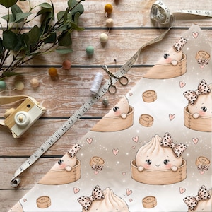 Könnte beinhalten: Ein hellbeiger Stoff mit einem wiederkehrenden Muster aus Cartoon-Teigtaschen in Bambusdämpfern, einige mit Leopardenmuster-Schleifen, durchsetzt mit kleinen rosa Herzen und weißen Glanzpunkten, mit einem 122 cm langen Maßband.