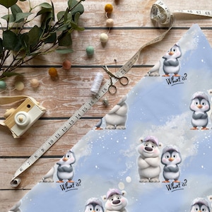 Könnte beinhalten: Hellblauer Stoff mit Cartoon-Pinguinen und Eisbären, mit dem Text "What is?". Ein Maßband zeigt Zentimeter, und Bastelmaterialien liegen auf einer Holzoberfläche.