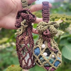 Pu&ograve; includere: Due sacchetti all'uncinetto con coulisse. Un sacchetto &egrave; marrone e verde e contiene una piccola bottiglia di vetro con un tappo di sughero. L'altro sacchetto &egrave; verde, marrone e blu e contiene piccole palline all'uncinetto.
