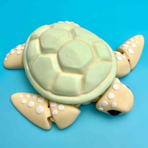 May include: A light green and yellow ceramic turtle figurine with a detailed shell and white dots on the limbs.