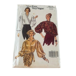 May include: A Very Easy Very Vogue sewing pattern envelope 8514 for sizes 8-10-12. The front displays three illustrations of blouses with voluminous sleeves, including a white ruffled blouse, a dark patterned blouse, and a gold wrap-style blouse.
