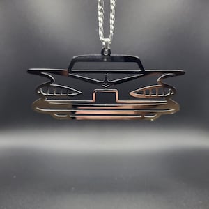 以下が含まれることがあります： 銀色のチェーンに吊るされた、クラシックカーのシルエットが詳細に描かれた銀色の車のチャームです。