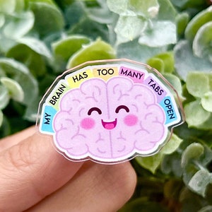 May include: A pink cartoon brain with a smiling face, surrounded by a rainbow-colored circle with the text "My brain has too many tabs open".