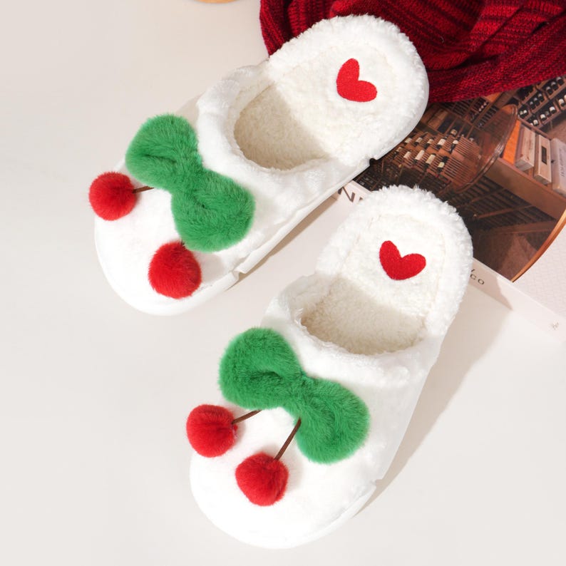 Pu&ograve; includere: Un paio di pantofole bianche e soffici con un design a ciliegia. Ogni pantofola presenta un fiocco verde, due accenti di ciliegia rossi e un cuore rosso. Le pantofole hanno un interno morbido e soffice.