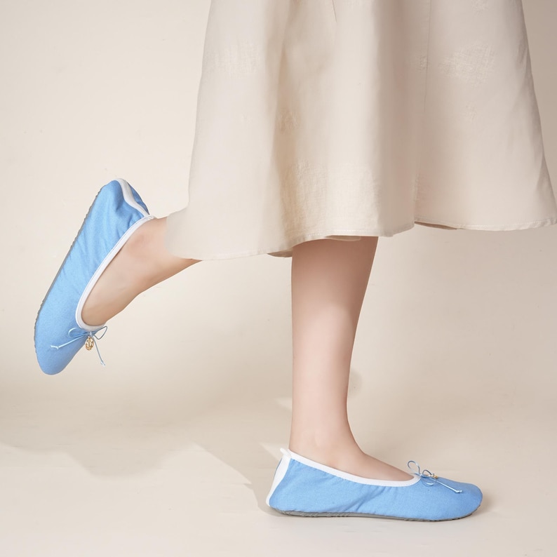 May include: A pair of light blue ballet flats featuring a white trim along the collar and a small decorative bow at the front. The shoes have a rounded toe design and a low-profile silhouette, providing a simple and clean look for casual footwear.