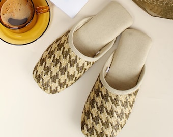 Può includere: Un paio di pantofole intrecciate beige e marroni con un motivo pied-de-poule. Le pantofole hanno una soletta morbida e imbottita e una calzata comoda.