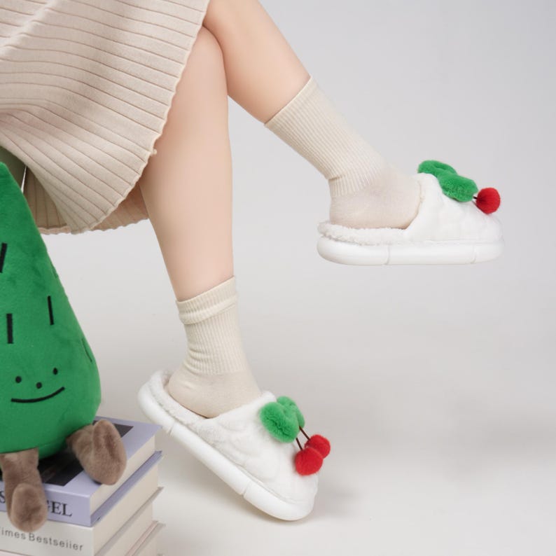 Pu&ograve; includere: Pantofole bianche e soffici con un design a ciliegia. Le pantofole hanno una consistenza morbida e una suola spessa. Il design a ciliegia presenta accenti rossi e verdi. Progettate per l'uso in casa.