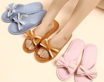 May include: Three pairs of women's slippers with bow accents. One pair is light blue, one pair is brown, and one pair is pink.