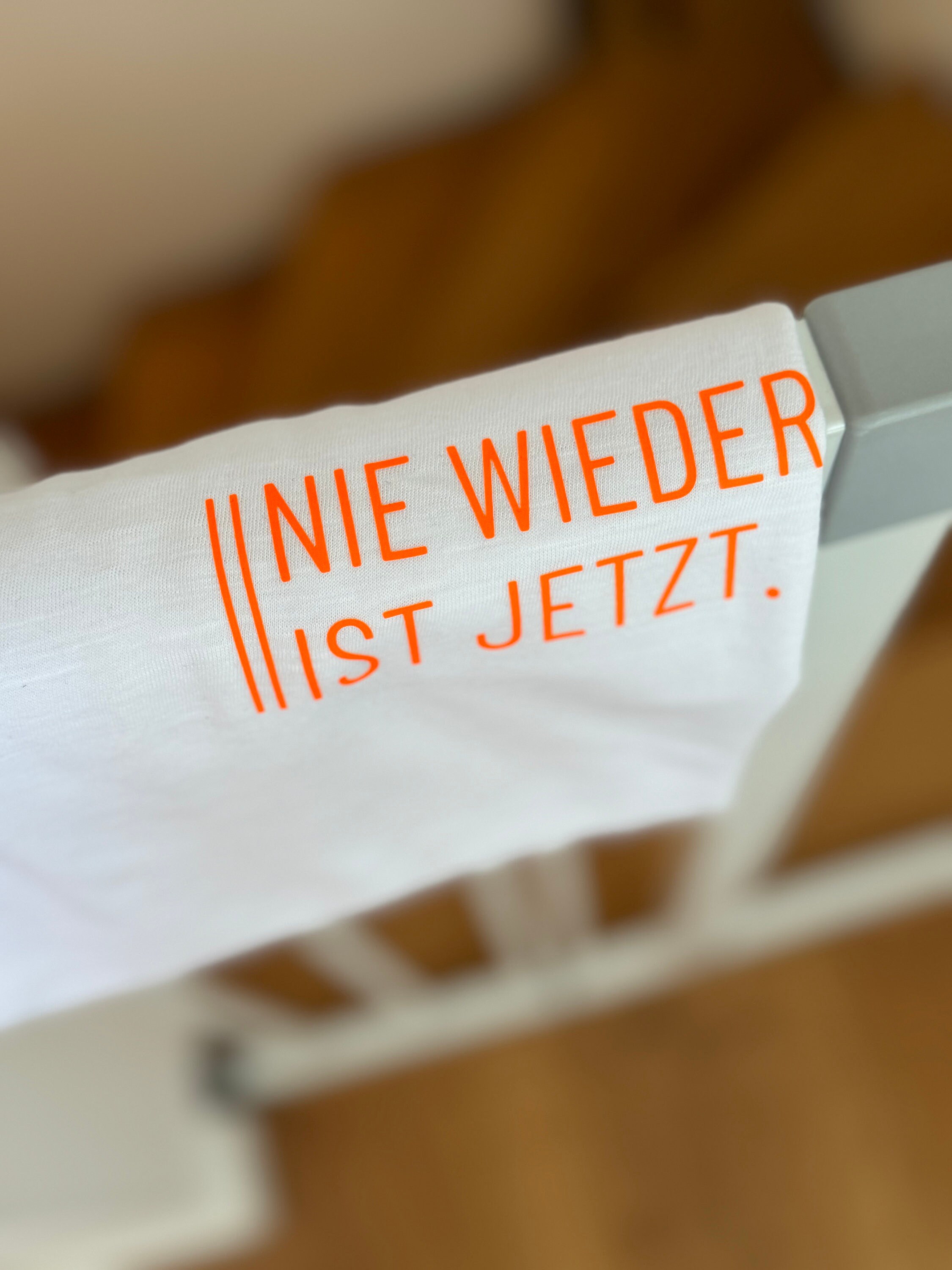 T-shirt with print - Never again is now. For women. White - neon orange. Sustainable & fair.