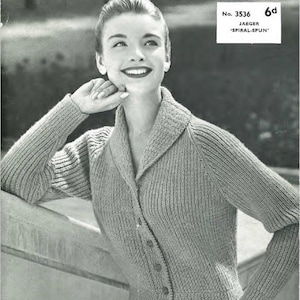 May include: A black and white photo of a woman wearing a gray knitted cardigan with a large collar. The cardigan has a button closure and is made of a textured fabric. The text "Jaeger" is printed in yellow at the bottom of the image. The text "No. 3536 Jaeger 'Spiral-Spun' 6d" is printed in the top right corner of the image.