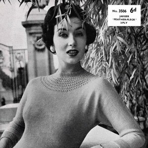 May include: A monochrome image of a woman in a light-coloured knitted sweater with a detailed neckline. The sweater has long sleeves and a ribbed hem. The word "JAEGER" is in yellow, stylized text at the bottom of the image.