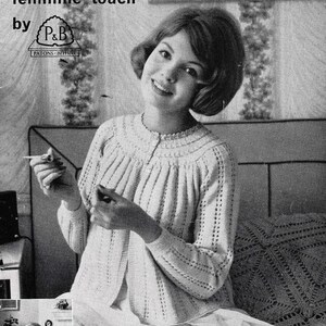 May include: A black and white vintage pattern illustration titled Two Bedjackets with the feminine touch by Patons Beehive, featuring a knitted cardigan with a round neckline, vertical ribbed texture, and long sleeves, worn over a skirt.